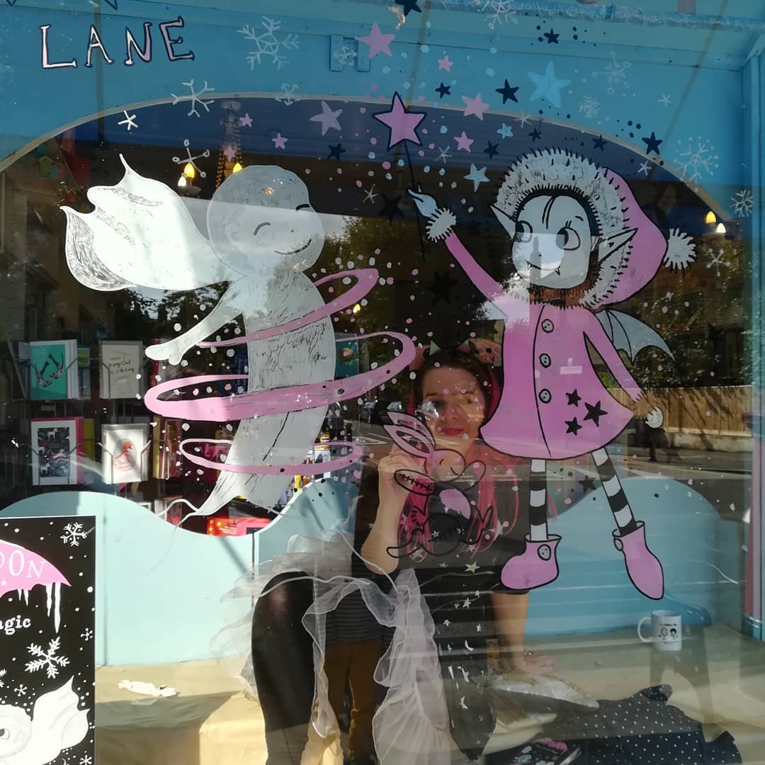 Harriet Muncaster painting window display for Tales on Moon Lane